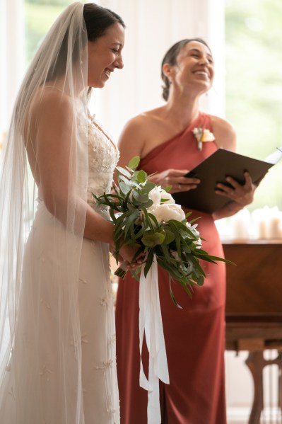 Close up of brides dress veil and flower detail bridesmaid in background